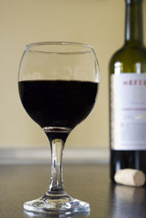 A glass of red wine and bottle with cork