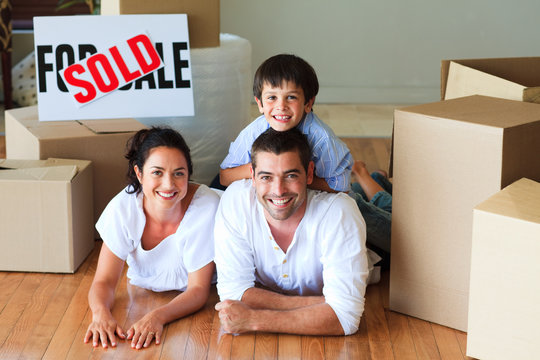 Family in their new house lying on floor with boxes