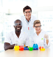 Scientists examining test-tubes smiling at the camera