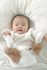 A beautiful smiling baby on white sheets