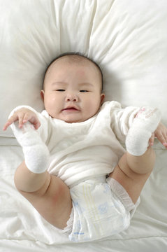 A beautiful smiling baby on white sheets