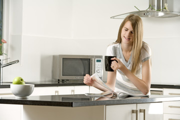 Fototapeta na wymiar Woman relaxing in kitchen reading
