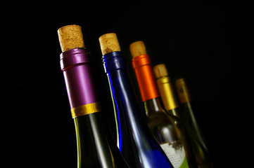 assorted wine bottles in a line, on black background