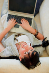 freundliche frau auf couch mit laptop