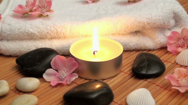 wellness time with candle, stones and blossoms