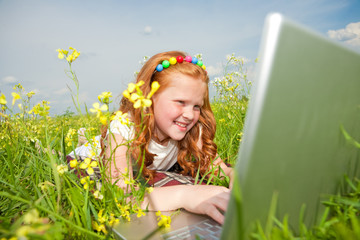 Fototapeta na wymiar Girl with laptop resting on meadow.