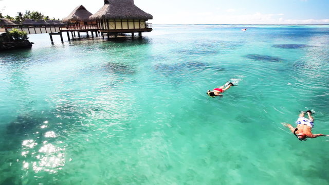 Young couple snorkeling in clean water next to resort