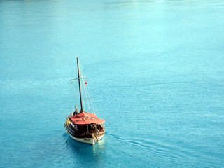 Chilliges Foto: Baues Wasser mit Segelschiff.  Das türkisblaue Mittelmeer an der Küste von Antalya in der Türkei. Türkischer Tourismus bietet Schiffsfahrten auf dem blauen Meer.