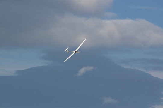 Glider soaring viewed against blue sky and clouds