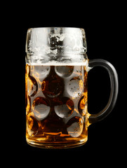 Glass of cold and fresh golden beer on black background