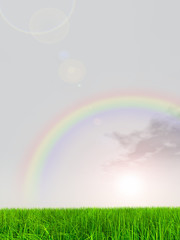 Obraz na płótnie Canvas green grass over a background sky with clouds and rainbow