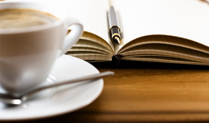 Open notebook with pen and cup of coffee