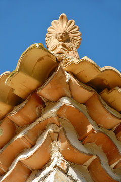 Ceramic antefix ornament on house rooftop in Greece