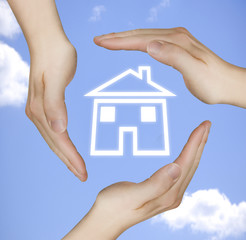 schützende Hände um ein Haus