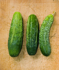 three green cucumber on wood table with selective focus