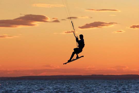 Windsurfer jumping at sea during sunset