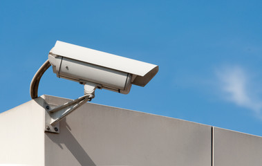 closed circuit tv surveillance camera against a light blue sky