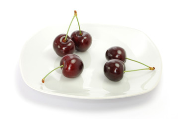 Fünf Süßkirschen auf weißem Teller