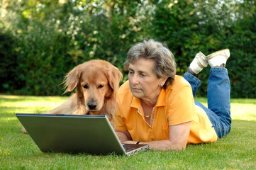 Seniorin am Laptop mit Hund