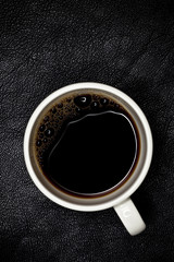 espresso coffee in white cup top view, black leather backdrop,