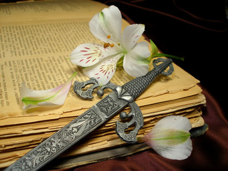 age-old book with a white flower and dagger on  yellow pages