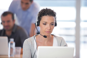 Femme assise devant un ordinateur portable avec un micro-casque