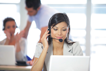 Femme souriante assise devant un ordinateur avec un micro-casque