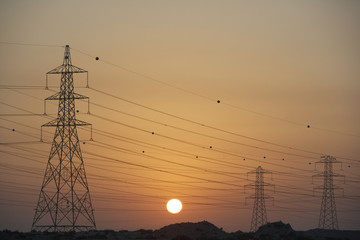Fototapeta premium Electricity Pylons Silhouetted At Sunset