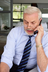 Homme senior assis à un bureau en téléphonant