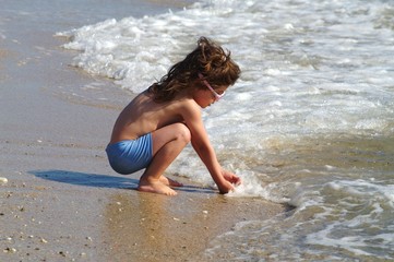 enfant qui joue avec les vagues