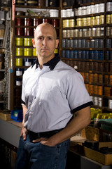 Worker standing in front of colored inks in print shop