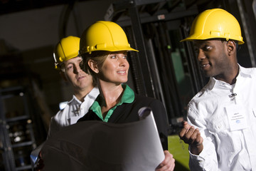 Office workers in storage warehouse wearing hard hats