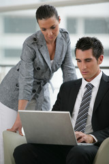 Fototapeta premium Homme sur un fauteuil devant un ordinateur près d'une femme