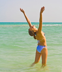Woman on a beach welcoming summer sun