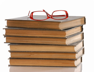 stack of books with a pair of reading glasses