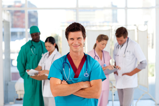Smiling doctor with his team in the background