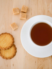 Cup of black tea, sugar and biscuits
