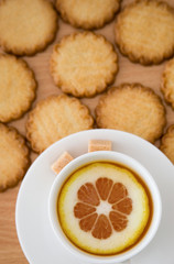 Cup of black tea with lemon, sugar and biscuits