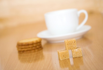 Cup of tea or coffee, sugar and biscuits. Focus on the sugar