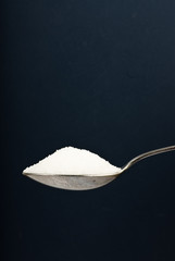 sugar on spoon blue background