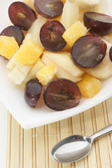 Obstsalat in einer weißen Schale mit Löffel