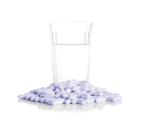 Glass with water and a heap of tablets, pills