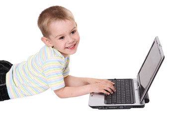 The boy lays behind the laptop looks and smiles