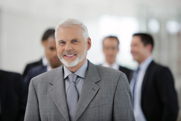 Homme d'affaires souriant en costume devant un groupe