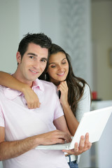 Jeune couple souriants devant un ordinateur portable