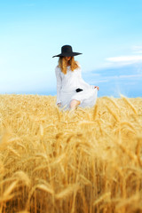 Fototapeta premium woman walking in summer wheat field