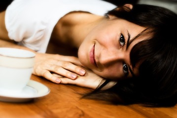 Obraz na płótnie Canvas Young smiling woman relaxing on the floor with a cup of coffee