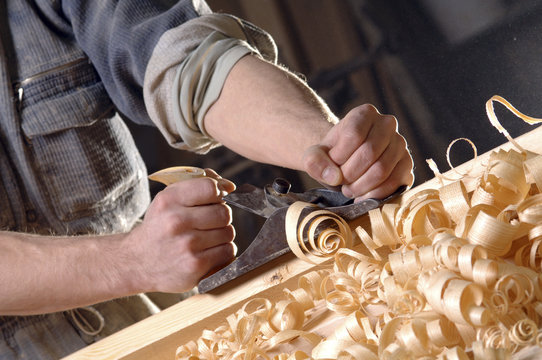 Man hands with carpenter's plane on wooden background