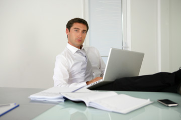 Homme assis à un bureau devant un ordinateur portable
