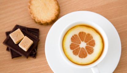 Cup of black tea with lemon, sugar, biscuits and chocolate